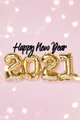 Happy New year 2021 celebration. Gold foil balloons numeral 2021 and fairy lights on pastel pink background. Flat lay, christmas creative concept