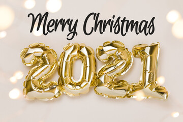 Merry Christmas celebration. Gold foil balloons numeral 2021, party decoration and confetti stars on beige background Flat lay, christmas creative concept