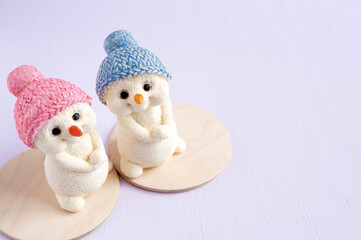 Snowman figures made of white chocolate sit back on a wooden background. Christmas card. Selective focus.