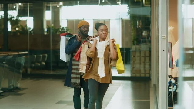 Shopaholic family. Afro-american stylish couple entering clothes store searching fashionable items together shopping in mall.