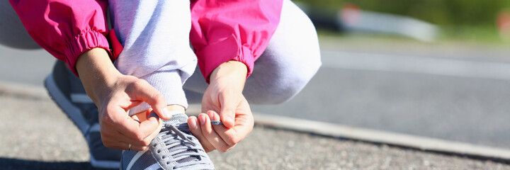 Close up of female hands tying shoes during morning run outdoors