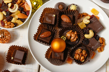 sweet food background for christmas or holiday decoration - chocolate candies, tangerines, nuts and dried fruits on white wood