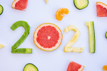 Exquisite fruits cut in the shape of the new year 2021 on a white table.