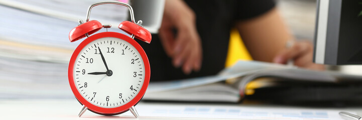 Naklejka premium Close up of alarm clock and tired female worker taking nap on huge pile of document folders on blurred background