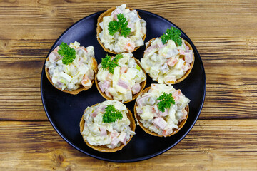 Traditional Russian festive salad Olivier in tartlets on wooden table
