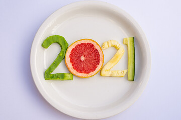 Delicious fruits cut in the shape of the new year 2021 on a white table.