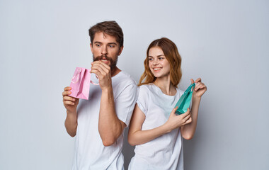 man and woman with gift bags stand back to each other on gray background