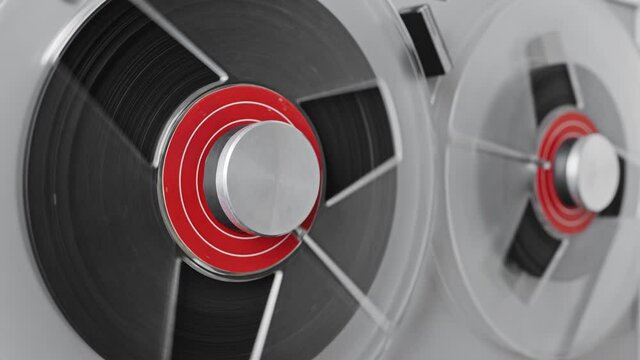 Reel to reel tape recorder playing. Rotating vintage music player close up. Retro tape. Spinning reels metallic color with red disc. View from above. Popular Disco Trends 60s, 70s, 80s, 90s.