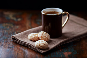 Amaretti (Italian biscuits) and a cup of coffee on rustic wooden background. Close up. 