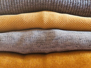 Yellow illuminated color and gray winter sweaters stack. Trendy fashion autumn warm and cozy clothes.
