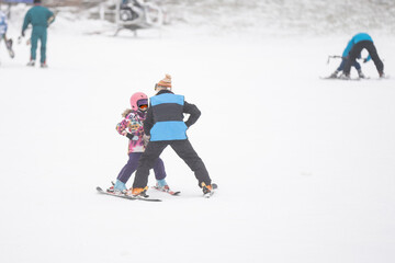 Fototapeta na wymiar Professional ski instructor is teaching a child to ski on a day on a mountain slope resort with snow. Family and children active vacation.