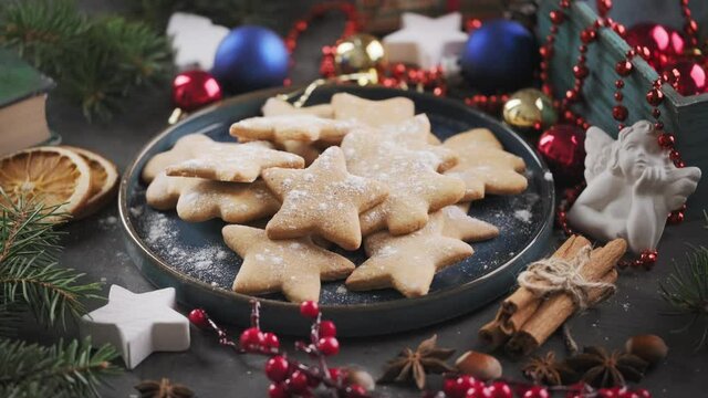 Christmas gingerbread cookies in a blue vintage plate, gifts and Christmas toys on a dark background, rotate around its axis. Presenting cookies on a plate, holiday plating.