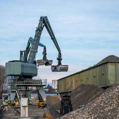 Big excavator working by handling pebbles from the pile of stones to container. Working machine in construction site.