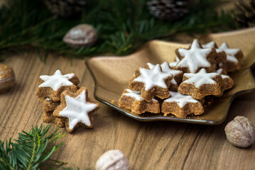 Christmas cookies in the shape of a star.  Branches of a Christmas tree, decorated nuts and cones on a wooden table.