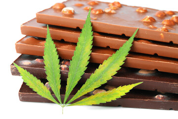 Chocolate bars and biscuits close-up with hemp leaf on white isolated background. Chocolate marijuana dessert cookies with CBD cannabis