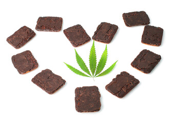 Green marijuana leaf in the middle of a heart made of chocolate biscuits which contain cannabis extract CBD on white isolated background