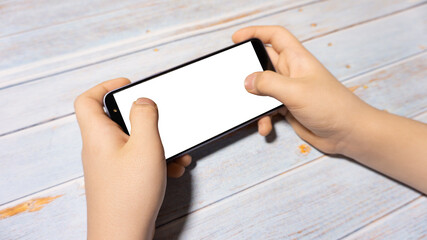 
The child is holding a phone with a white screen at the table. Child's phone with white screen