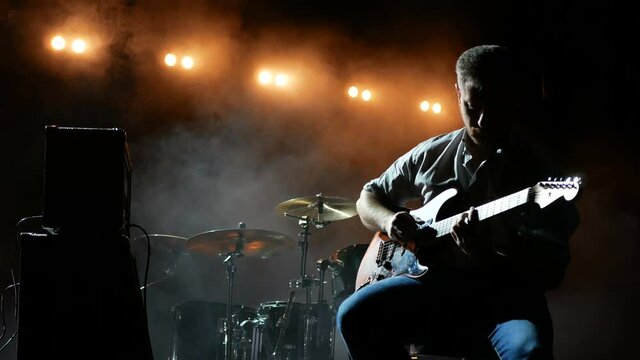 Musician silhouette, guitarist playing electric guitar.
