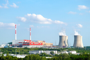 Fototapeta na wymiar Panoramic view on nuclear power plant with steaming cooling towers on the background of blue sky
