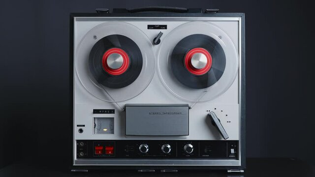 Man hand turns on music on reel to reel tape recorder playing. Rotating vintage music player close up. Retro tape. Spinning reel. Party. Loop. Front view. Front view. Popular Disco Trends 60s, 70s, 80
