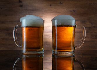 Two glasses of golden beer on wooden background