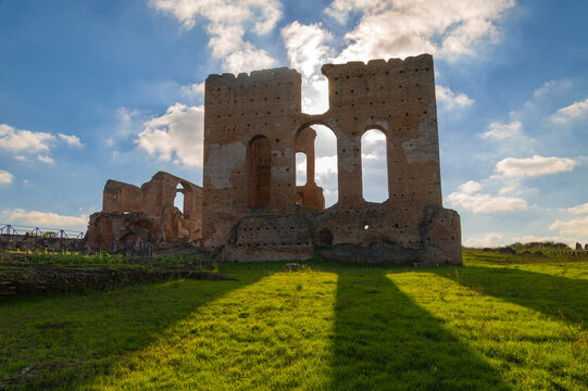 Imposing remains of the Villa dei Quintili, Rome, the thermal baths, a suggestive panoramic of the caldarium and then frigidarium with the blue sky, clouds and shadows on the green lawn. Appia Antica.