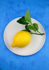 Limone fresco con foglie isolato su sfondo blu. Vista dall'alto.