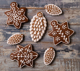 Christmas Gingerbread on brown wooden background. Snowflake, and cones shape.