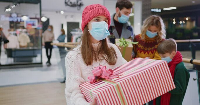 Portrait of excited pretty caucasian girll teenager dancign with her Christmas present enjoying holiday shopping with family smiling into camera. Family tradition. Christmas.