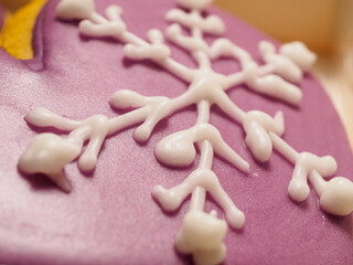 Gingerbread glaze cookie of lilac glove with snowflake, close up. Traditional Christmas food. Christmas and New Year holiday concept..Hand painted. Comfort food. Christmas treat.