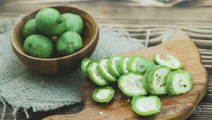 healthy food. Walnuts, cut into slices, are scattered on a cutting board. Old vintage table and whole unripe walnut fruit
