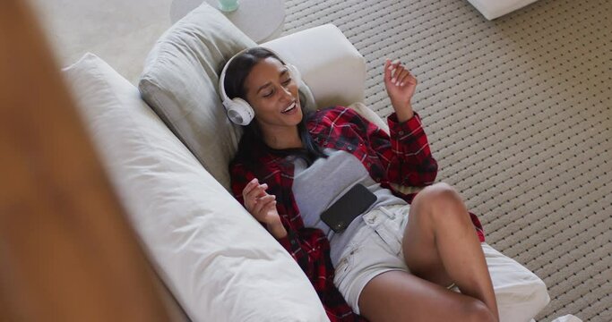 Mixed race woman using a smartphone, listening to music with headphones on