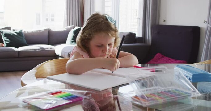 Caucasian girl drawing in notebook in living room