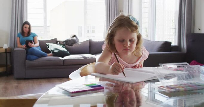 Caucasian girl drawing in notebook in living room