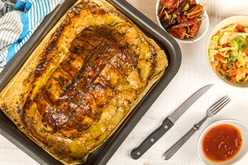 Baked minced meat with chili spices and sausage. Making classic meatloaf with ground beef. Tasty baked turkey meatloaf with bacon on wooden board.