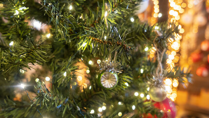 Obraz na płótnie Canvas Defocused green ball is on fir Christmas tree. Close-up image of green New Year toy decoration on yellow background. Happy New Year concept.