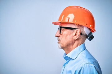 Mature engineer in black glasses and a protective helmet