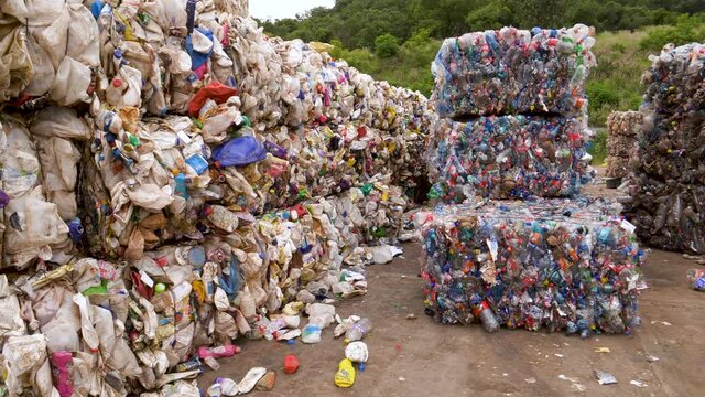 Plastic pollution.  Panning view of compressed and tied up blocks of plastic bottles awaiting recycling at a recycling plant