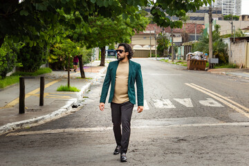 Homem elegante, usando óculos de sol e blazer, caminhando na rua.