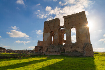 Villa dei Quintili, Rome, the thermal baths, a suggestive panoramic image of the brick building of the caldarium at sunset with the sun rising from the ruins and the blue sky in Via Appia.