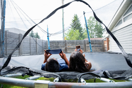 Children using digital devices on trampoline