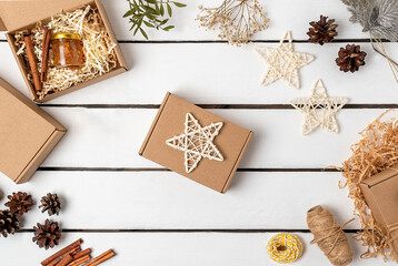 Flat lay of gift craft boxes, pine cones, cinnamon sticks, dried flowers and Christmas decorations on a wooden light background. Eco friendly christmas.