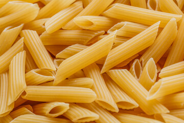 Dry pasta Pennoni Rigati.Pennoni Rigati have shape and yellow color. Pasta is delicious Italian traditional food made from wheat flour like noodles.Dry pasta background.Top view