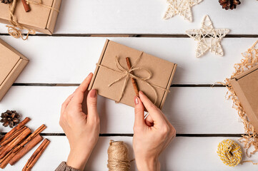 A woman is packing gifts in a craft gift box. Eco friendly Christmas. Wasteless.