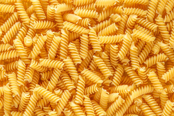Dry pasta fusilli. Fusilli have spiral shape and yellow color. Pasta is delicious Italian traditional food made from wheat flour like noodles.Pasta background.Top view