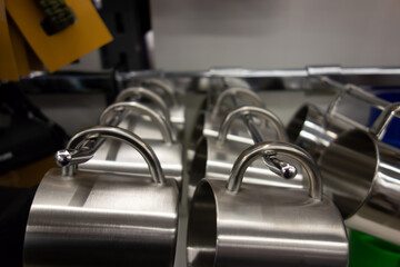 metal mugs hang on a rod on a shelf in a store