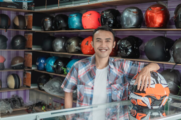 male shop assistant standing with his hand resting on a helmet in a helmet shop