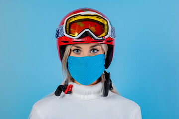 Close-up portrait of a girl skier wearing a light blu protective mask, helmet and glasses. A...
