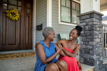 Portrait of mother and daughter sitting on front porch steps
