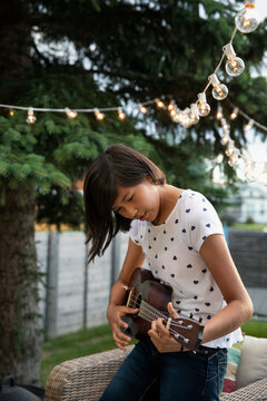 Portrait of girl playing ukulele in backyard